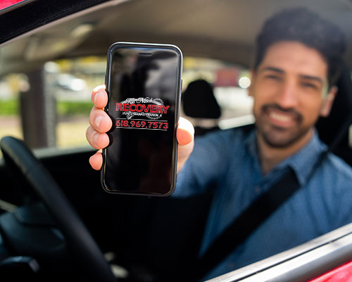Man in drivers seat of car holding phone with Top Notch Recovery on screen