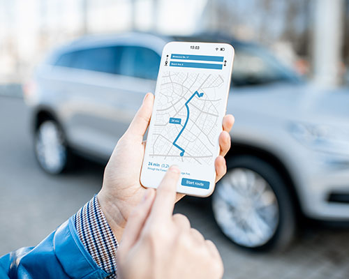 Hands holding a phone pointing to gps with suv in the background