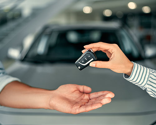 Handing over keys with blurry car in the background